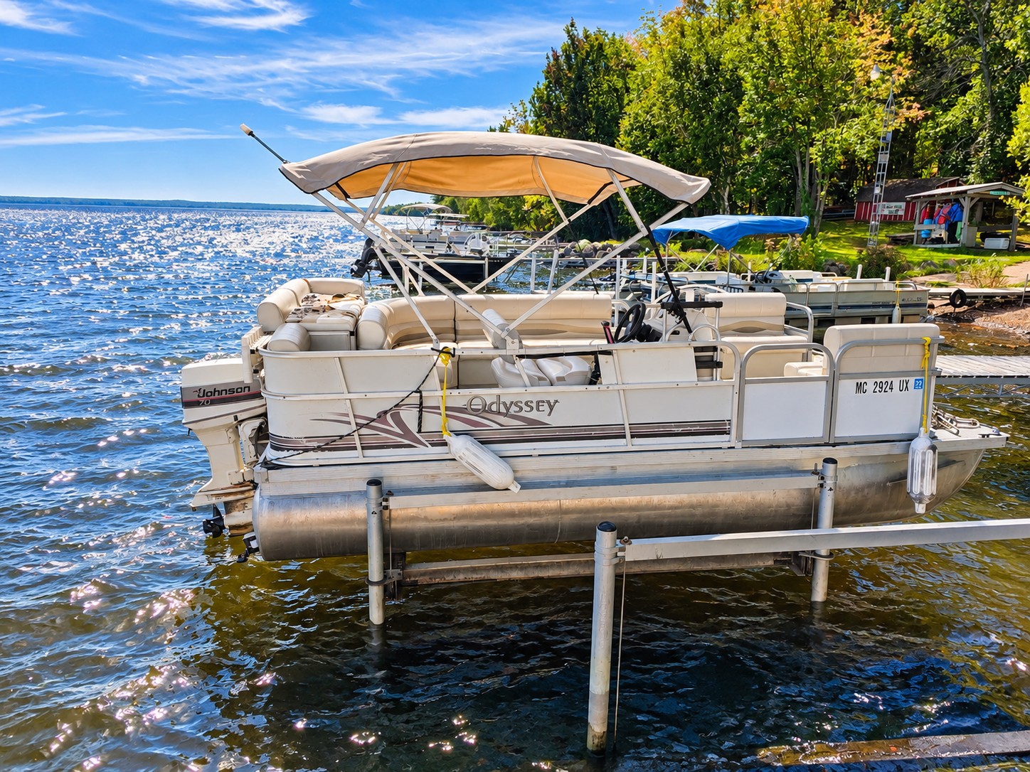 Odyssey pontoon with cushioned seating and a tan canopy on a lift at the resort dock